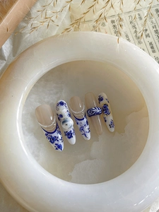 Detailed view of Chinese porcelain style nails with blue floral art and pearl accents