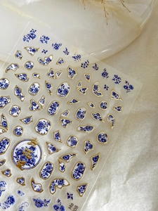 Detail of blue and white porcelain nail stickers with gold foil edges and floral patterns