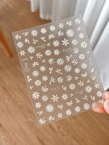 Detail showing 3D embossed white and yellow daisy nail stickers with adhesive backing