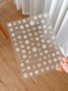 Close-up of 3D embossed daisy nail stickers with white petals and yellow cores