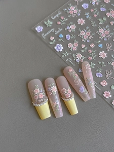 Detail of 3D embossed floral nail stickers with purple flowers and bow on matte nails