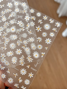 Detailed macro view of 3D embossed white daisy nail art stickers with yellow centers
