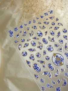 Detailed view of blue and white porcelain nail art decals with elegant gold embossing