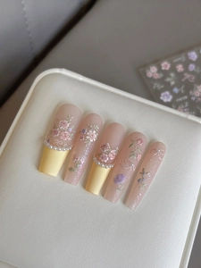 Detailed macro view of 3D embossed floral nail art with pearls and pink gradient design