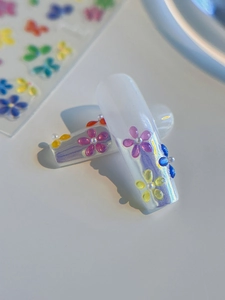 Detailed macro view of 3D colorful jelly flowers and pearl charms on pearlized nails