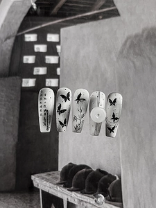 Detailed view of ink style nail art with butterfly and bamboo motifs on long coffin nails