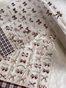 Detail of bow-knot nail art stickers featuring brown plaid patterns and autumn-themed designs