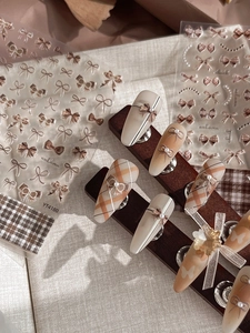 Detailed view of 3D autumn bow nail art stickers with plaid patterns and pearls