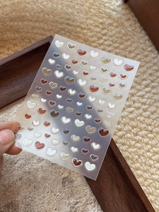 Detail of 3D jelly heart nail stickers with gold outlines in warm earth tones