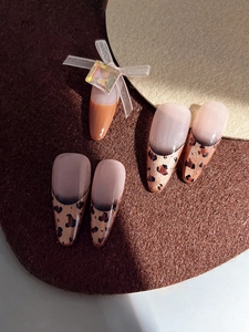 Detail of autumn-style press-on nails with leopard print and a rhinestone bow accent
