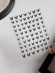 Macro detail of black and white butterfly nail art stickers with vintage ink ink style