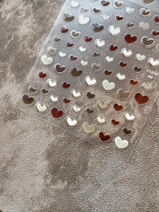 Detail of 3D jelly heart nail stickers with gold metallic frames and latte brown tones