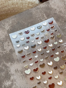 Macro shot of 3D jelly heart nail art stickers with golden metal outlines and adhesive back