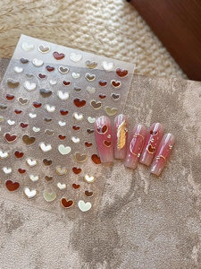 Macro shot of 3D gold heart nail stickers with metallic borders and jelly finish