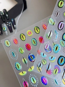 Detail of laser cat eye nail stickers with colorful evil eye patterns and glitter effect