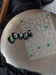 Macro shot of gothic emerald green snake nail stickers with silver star details