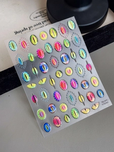 Detailed macro view of 3D monster evil eye nail stickers with holographic laser effects