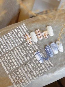 Detail of 3D embossed nail art stickers with white sweater texture and cable patterns