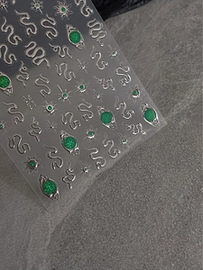 Detail view of emerald green snake nail stickers with silver outline and glitter eye design