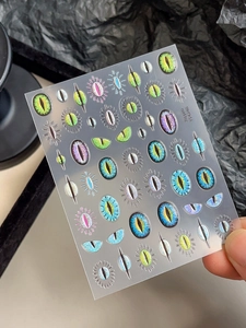 Detail of laser cat eye nail stickers with reptile eye designs and metallic finish