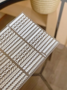 Detail of white 3D embossed nail art sticker with woven textures and wave patterns