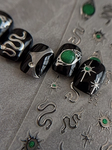 Macro detail of snake relief and green gemstone inlay on black polished nail stickers