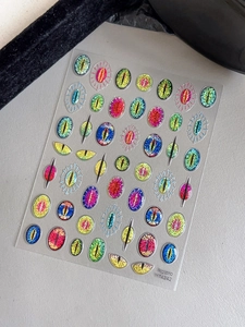 Macro detail of shimmer texture devil eye nail art stickers in various vibrant colors