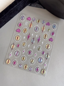 Glittery evil eye nail stickers with heart and star patterns on a textured background