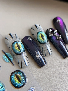 Macro shot of 3D dragon eye design and silver cross charms on long ballerina press-on nails