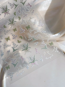 Close-up of embossed lily of the valley and bow nail stickers with butterfly details