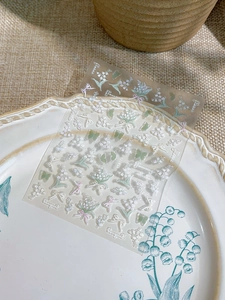 Detail showing 5D embossed lily of the valley and butterfly nail art stickers on ceramic