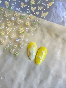 Detailweergave van gele vlinder nagelstickers met witte bloemen en groene bladeren