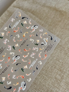 Macro shot of 3D embossed koi fish and lotus flower nail art stickers with calligraphy