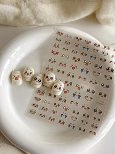 Detail of cute facial expression nail art stickers and finished nails on white tray