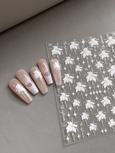 Détail des stickers d'ongles gaufrés blancs à fleurs sur faux ongles rose nude cat-eye