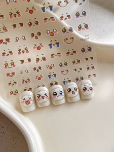 Detail of cute facial expression nail stickers on a white nail tip palette model YT3904