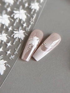 Détail d'autocollants 3D en relief fleurs blanches et étoiles sur des ongles rose nacré