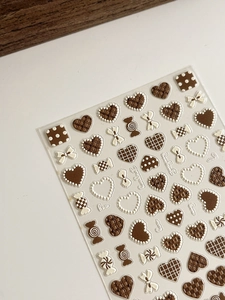 Detail of 3D embossed heart and bowknot nail art stickers in brown and cream tones