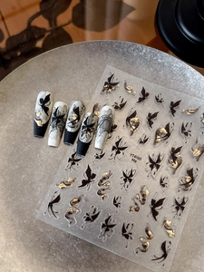 Dettaglio di adesivi per unghie con farfalle inchiostro nero e foglie d'oro su punte lunghe