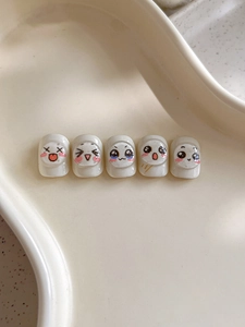 Detail of 3D embossed cute emoji nail stickers on white press-on nails in cream ceramic tray