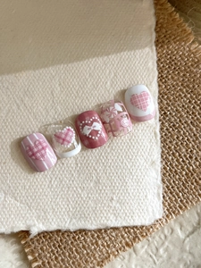 Detail view of 5-piece pink and white press-on nails with 3D bows and candy motifs
