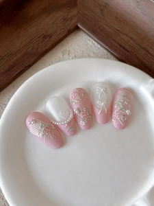Detail of pink relief flower nail tips with pearls and 3D floral embroidery textures