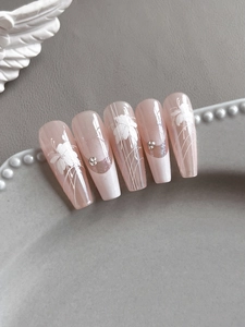Détails de faux ongles ballerine avec motifs floraux et accents de paillettes délicats