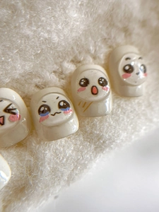 Macro shot of cute cream-colored cartoon expression nail art stickers on white faux fur