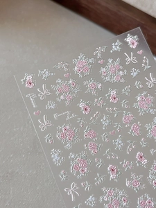 Detail of 3D embossed floral nail stickers featuring pink flowers and white bows