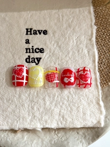 Detail of 3D embossed heart and bowknot press-on nails with red checkered patterns