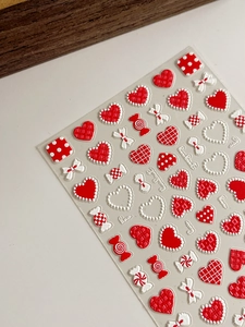 Macro view of 3D embossed nail stickers featuring red hearts and bowknot textures