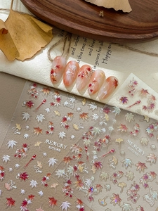 Close-up of autumn maple leaf nail stickers with bird motifs and warm fall colors