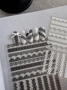Macro detail of black and white lace nail art stickers with intricate floral patterns
