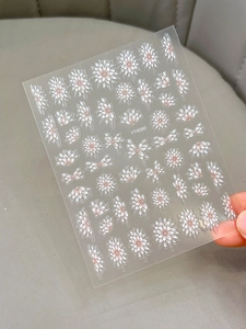 Macro shot of semi-transparent floral nail stickers with white daisy petals and pink centers